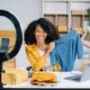 Woman blogger showing clothes in front of the camera to recordin T-Shirt Beratung per Video