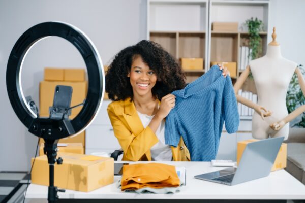Woman blogger showing clothes in front of the camera to recordin T-Shirt Beratung per Video